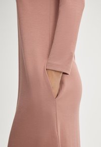 Sukienka typu jersey w kolorze zgaszonego różu, z kieszenią w bocznym szwie, rękawami o długości trzech czwartek oraz gładką, miękką fakturą na ciele.
