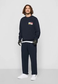 Laivastonsininen collegepaita logopreventillä, puuvillasekoitekangasta, resorihihansuut, yhdistetty yhteensopiviin laivastonsinisiin housuihin ja valkoisiin tennareihin. Rakenteelliset mustat hansikkaat.