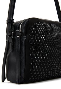 Borsa a tracolla nera con pelle texturizzata, accenti lisci, chiusura con zip e un design borchiato su un lato.