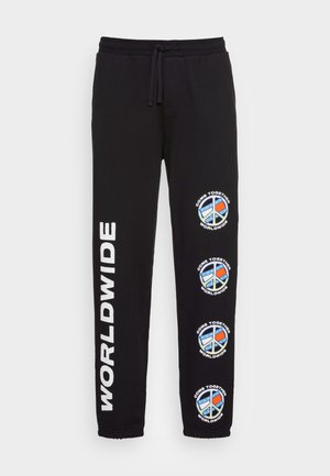 Schwarze Jogginghosen mit weißem "WORLDWIDE"-Text am linken Bein und drei Friedenssymbol-Logos mit roten und blauen Akzenten. Elastischer Bund mit Kordelzug.