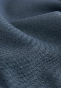 Dunkelblaues Gewebe mit einer glatten Textur, das ein geripptes Strickmuster aufweist, das subtile Bewegung und Tiefe erzeugt.