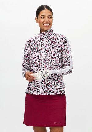Witte zip-up jas met luipaardprint in roze en zwart, voorzien van lange mouwen en een hoge kraag, gecombineerd met een bordeauxrode rok.