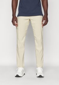 Beige chinos med rak passform, gjorda av bomull. Matchade med vita sneakers med svart sula och en marinblå t-shirt.