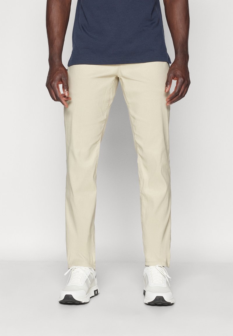 Beige chinos med rak passform, gjorda av bomull. Matchade med vita sneakers med svart sula och en marinblå t-shirt.