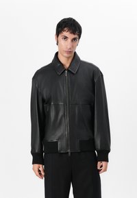 Black leather jacket with a zip front, wide collar, ribbed cuffs, and a smooth texture. Features front pockets and a relaxed fit design.