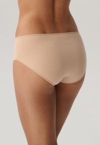Beżowe bawełniane majtki o gładkiej fakturze, w kroju średniego stanu, z zaokrąglonymi brzegami. Prosty design bez widocznych szwów i wzorów.