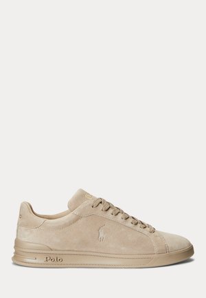 Beige suède lage sneaker met beige veters, geperst Polo-logo aan de zijkant en een getextureerde rubberen zool op een witte achtergrond.
