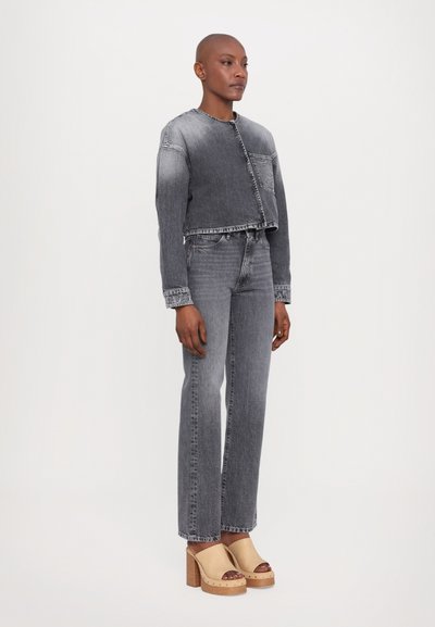 Jachetă din denim de culoare gri estompată, cu un design scurt și închidere cu nasturi în față. Blugi gri asortați cu croială dreptă. Saboturi cu platformă de culoare deschisă.