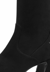 Black suede ankle boot with a sleek, fitted design. Features a contrasting shiny heel and minimal stitching details.