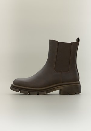 Bottine en cuir marron foncé à la cheville avec panneaux élastiques latéraux, languette à l'arrière, semelle en caoutchouc épaisse et petit talon bloc.