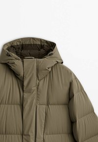 Veste d'hiver matelassée vert olive avec col montant et capuche ajustable, vue de face sur fond blanc.