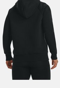 Sweat-shirt à capuche noir en tissu polaire texturé. Doté de poignets et d'un ourlet côtelés, conçu avec une coupe décontractée et une capuche spacieuse.