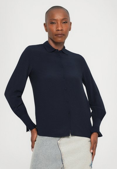 Laivansinis blouse, jossa on kaulusk Dec, napitettava etuosa ja pitkät hihat, joissa on laskostetut hihansuut. Silkkinen kangas.