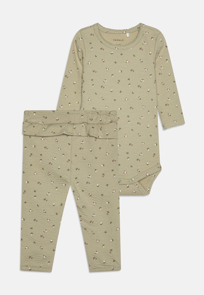 Twee-delig set met een langemouwen bodysuit en bijpassende broek. Licht olijfgroen stof met kleine bloemenpatronen en geschulpte randen.