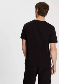 Czarna koszulka z okrągłym dekoltem, wykonana z miękkiej, lekkiej bawełny, o luźnym kroju. Prosty design, krótkie rękawy i brak widocznych logo lub wzorów.