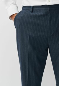 Marineblau gestreifte Hose mit geradem Schnitt, aus glattem, leichtem Stoff gefertigt. Verfügt über einen schmalen Bund und seitliche Taschen.