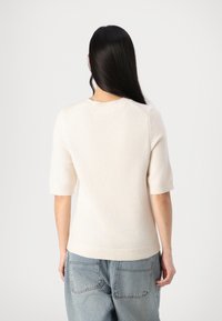 Helles beige Strickpullover mit kurzen Ärmeln, gerippten Bündchen und rundem Halsausschnitt. Mit einer weichen Textur und lässigem Schnitt.