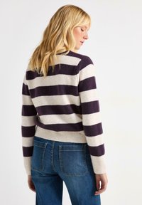 Strikket sweater med markante lilla og creme horisontale striber, rund halsudskæring og ribbet kant. Sammen med afslappede denimjeans.