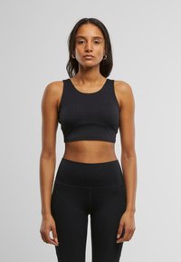 Svart, kort athletic topp med rund hals og tykke stropper, laget av et glatt, elastisk materiale, sammen med matchende høy midje tights.
