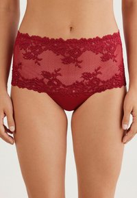 Rote Spitzenunterwäsche mit einem Blumenmuster am Bund, darunter glattes Material für Komfort und Bedeckung.