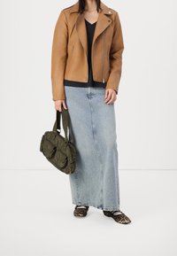 Chaqueta de motociclista de cuero marrón, blusa negra de cuello en V, falda larga de mezclilla azul claro, bolso texturizado verde y manoletinas de estampado de leopardo.