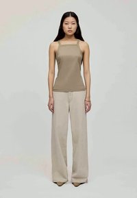 Top sin mangas beige con escote cuadrado, combinado con pantalones de pierna ancha beige claro. Textura de tela suave, diseño minimalista, zapatos de punta.