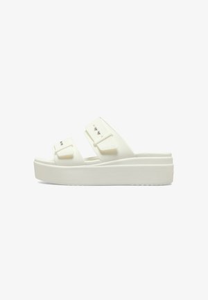 Sandales à plateforme blanches avec deux larges brides ornées de boucles et de clous en métal. Fabriquées en matériau durable, texture lisse.