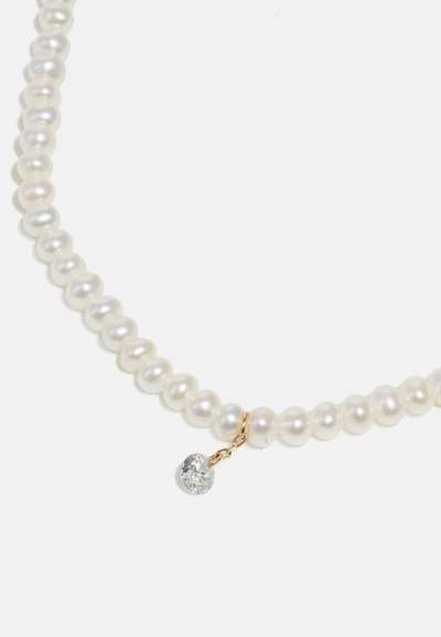 Pērļu kaklarota, kurā ir apaļas baltas pērles ar gludu virsmu, papildināta ar zelta aizdari un vienu karājošu caurspīdīgu dārgakmeni.