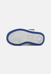 Shoe sole featuring a textured white rubber base with blue accents and geometric patterns, designed for traction and durability.