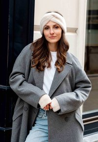 Gray wool overcoat with a wide collar and large buttons, paired with a white shirt and denim. Features plush cream accents on cuffs and headband.
