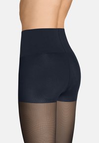 Hochtaillierte Leggings in Dunkelblau mit einem durchsichtigen braunen unteren Abschnitt und einem strukturierten schwarzen oberen Teil, der einen sanften Übergang an der Taille betont.