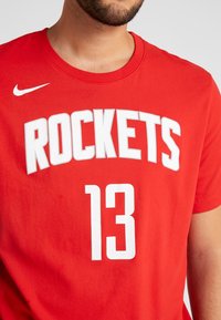 Czerwona bawełniana koszulka z krótkim rękawem, z napisem „ROCKETS” dużymi białymi literami oraz numerem „13” poniżej w perforowanym stylu.