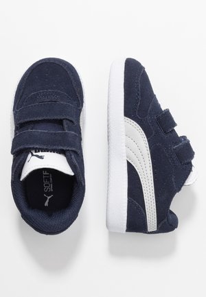 Marina mockasiner i mocka med vita läderdetaljer. Har kardborreband och strukturerade vita gummisålar. Inkluderar logotyp på tungan.