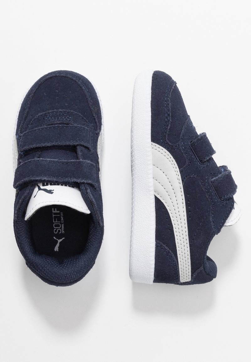 Marina mockasiner i mocka med vita läderdetaljer. Har kardborreband och strukturerade vita gummisålar. Inkluderar logotyp på tungan.