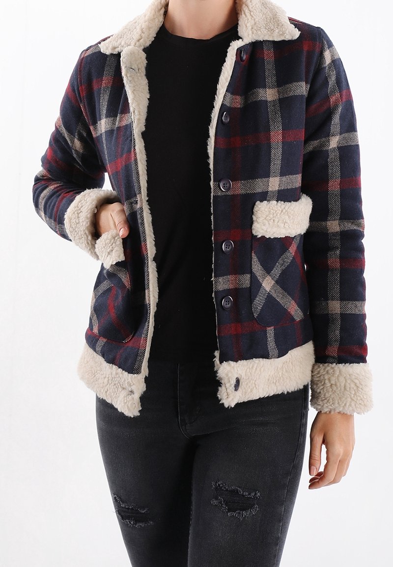 Ruutukuosinen takki laivastonsinisellä, viininpunaisella ja beigen sävyllä, jossa on sherpa-kaulus ja kalvosimet. Takissa on napitus ja kaksi sivutaskua.