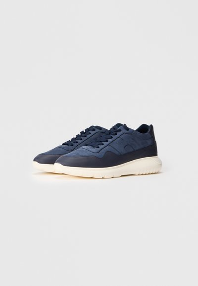 Baskets en cuir bleu marine avec des accents texturés et des lacets ton sur ton, dotées d'une semelle en caoutchouc crème rembourrée et d'un design arrondi.