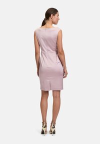 Abito senza maniche di color rosa con una silhouette aderente, tessuto satinato morbido e zip sul retro. Abbinato a tacchi alti con dettagli dorati.