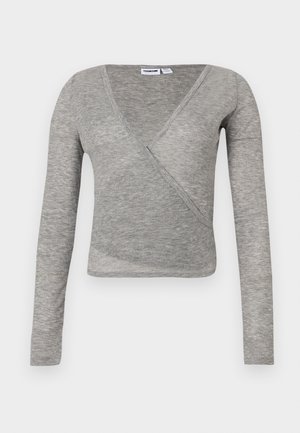 Top gris à manches longues avec effet cache-cœur et texture côtelée. Caractérisé par un décolleté en V profond et une coupe cintrée, idéal pour superposer ou porter de manière décontractée.