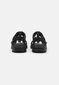 Svart åpne sandaler med justerbare stropper, teksturert såle og en robust gummi såle for godt grep. Designet har flere stropper.