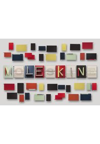 Collezione di vari quaderni Moleskine in diverse forme e colori, tra cui rosso, giallo, blu, verde, nero e bianco, disposti in modo artistico.