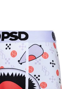 Vita boxershorts med en svart och röd hajgrafik, tillsammans med lila och orange geometriska mönster, och en svart logoband.