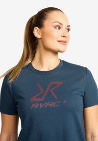 Dark blue fitted T-shirt with short sleeves, featuring a red graphic logo at the center. Soft, stretchy cotton material.