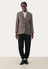 Bruine tweed blazer met een opvallende kraag en drie zwarte knopen, gecombineerd met zwarte cargobroek en zwarte schoenen. Gladde textuur, tailor-made pasvorm.