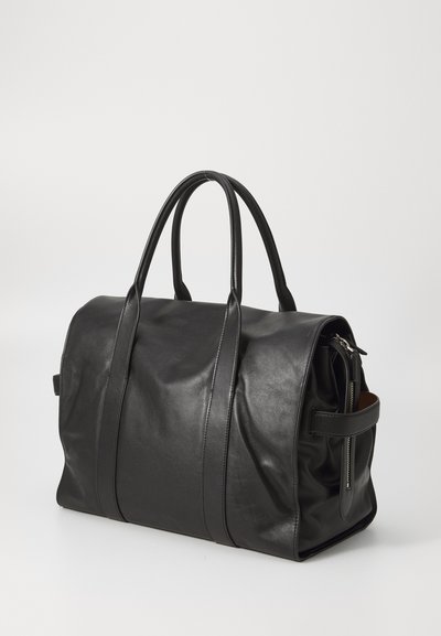 Borsa da viaggio nera in pelle con texture liscia, forma arrotondata, doppi manici e chiusura a zip. Tasca laterale con hardware in argento.