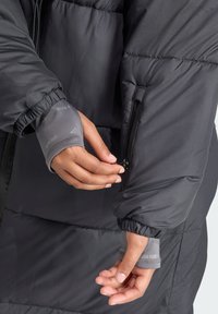 Puhasti kaput u tamno sivoj boji, s elastičnim manžetama i bočnim džepom sa zipom. Smanjena tekstura sa šivenim segmentima za izolaciju.