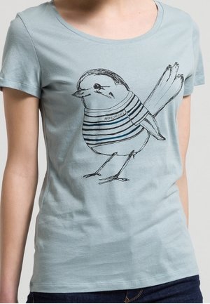 Jasnoniebieska koszulka z czarnym, liniowym rysunkiem ptaka ubranego w paskowany sweter, umieszczonym na środku klatki piersiowej.