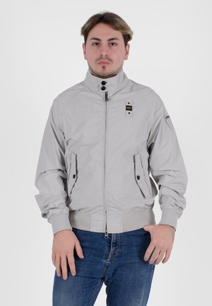 Giacca bomber grigia chiara con colletto alto, chiusura con zip, due tasche laterali, polsini elasticizzati e un sottile marchio sulla spalla.