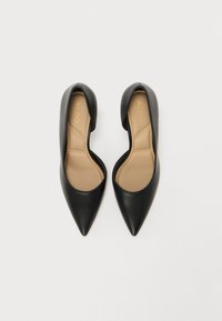 Black leather pointed-toe shoes with a v-shaped cutout and a beige insole. Smooth texture and minimalistic design, no visible hardware.