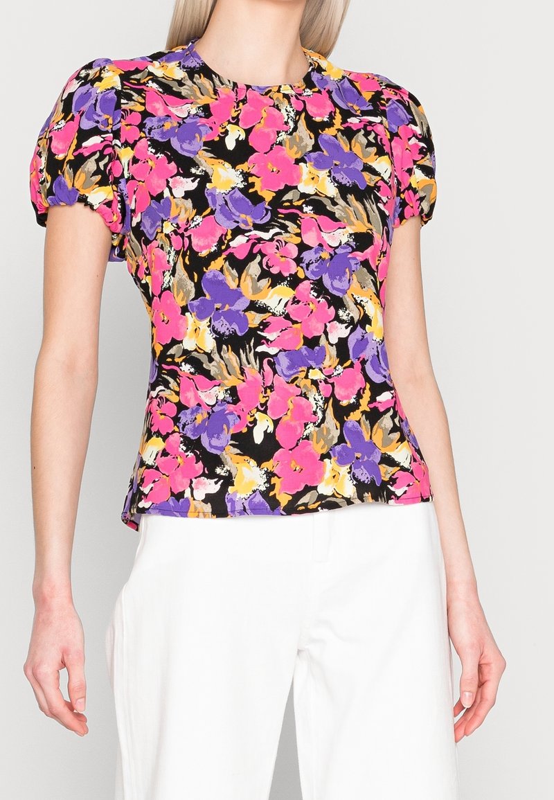 Haut à imprimé floral avec manches bouffantes dans des tons de rose, violet, orange et noir. Le tissu semble léger avec une texture lisse.