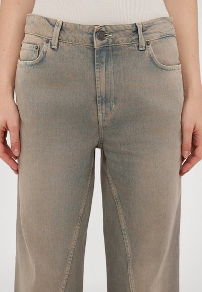 Beige Denim-Jeans mit geradem Bein, featuring Fronttaschen, einem Knopfverschluss und Kontrastnähten. Glatte, leicht verblasste Textur.